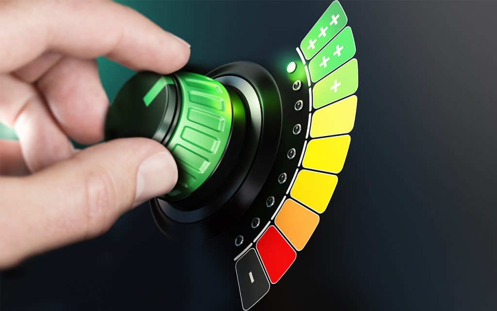 Dial showing color coded energy efficiency rating scale for buildings, fingers turning dial to highest efficiency rating (green+++) Best energy reduction method