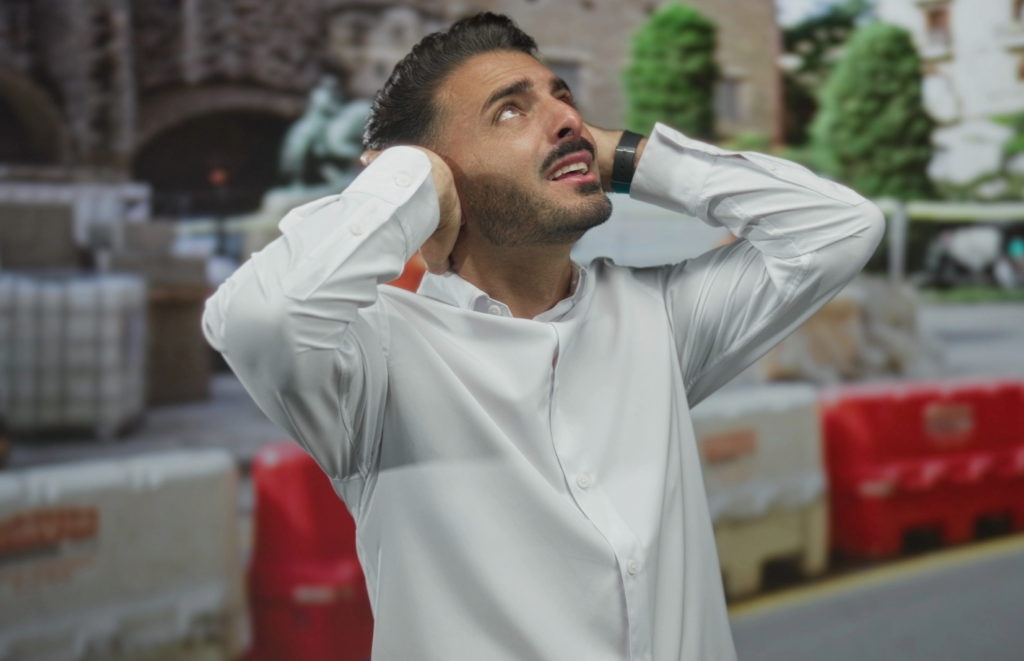 Loud HVAC Noise outside, Man with hands on ears looking up
